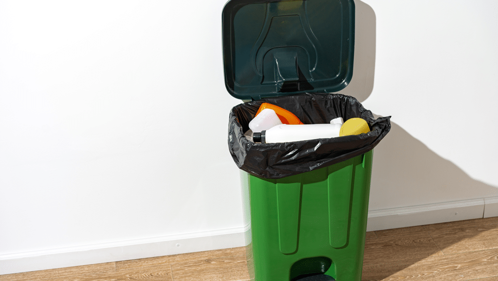 green-plastic-trash-can-full-garbage-indoors