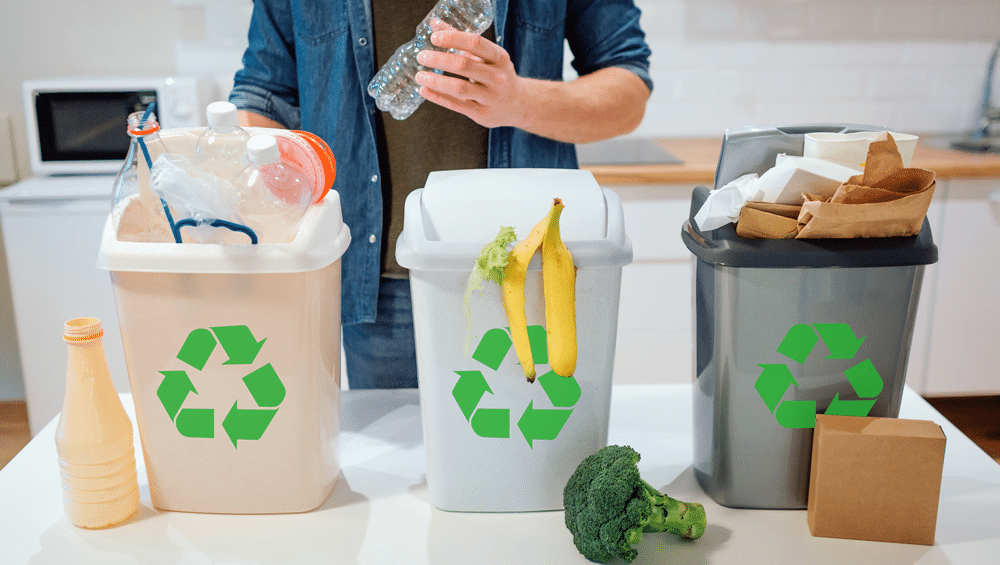 man putting plastic bottle in garbage-bin in kitchen